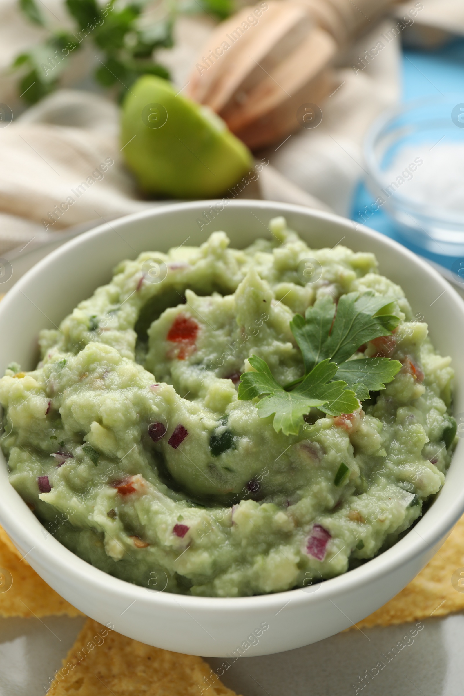 Photo of Delicious guacamole served with nachos chips on table