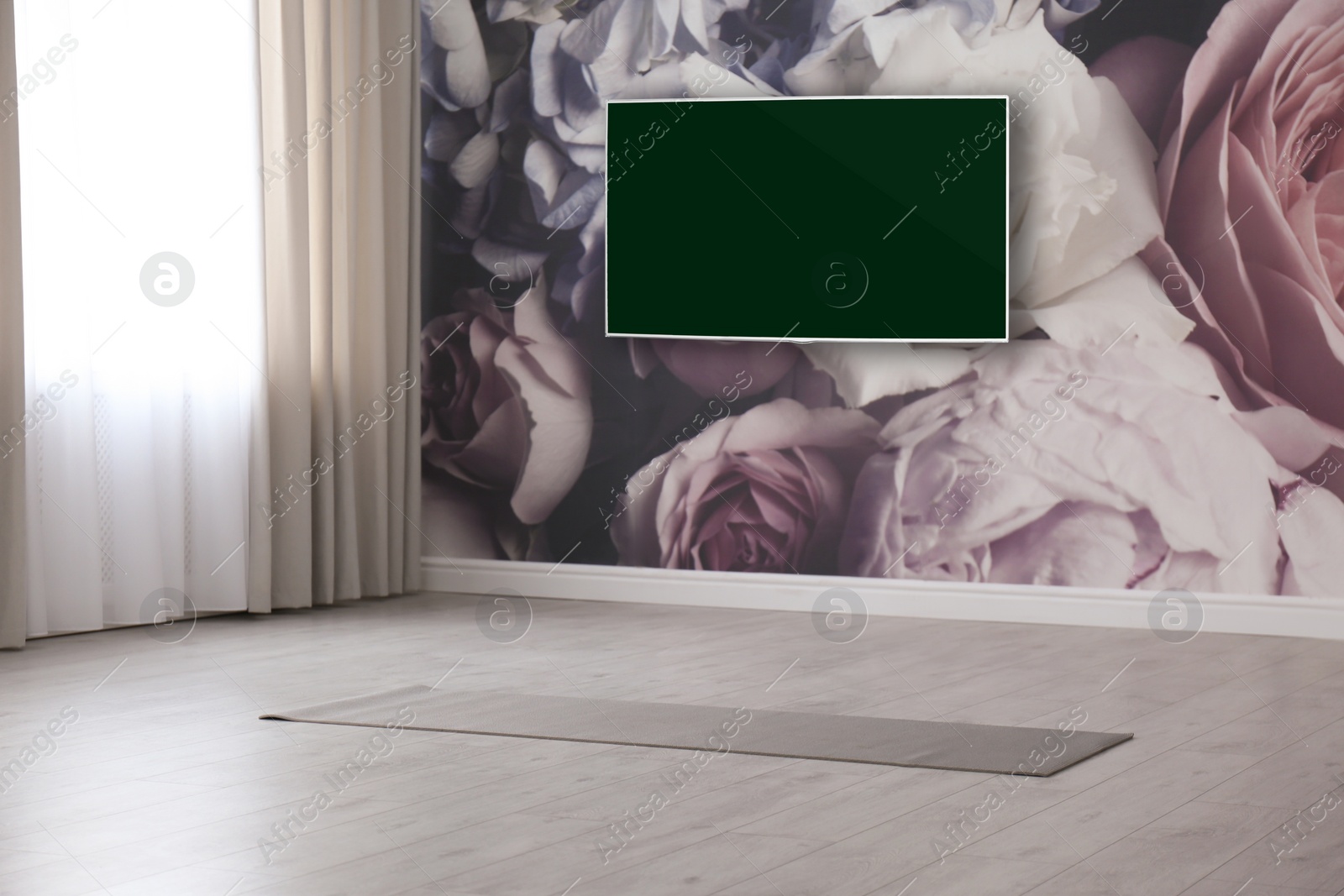 Image of Modern wide screen TV on wall in room with yoga mat