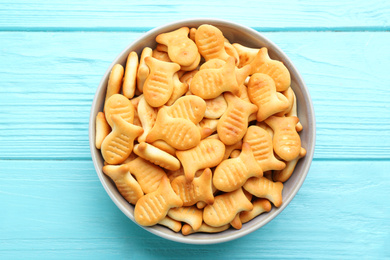 Delicious goldfish crackers in bowl on light blue wooden table, top view