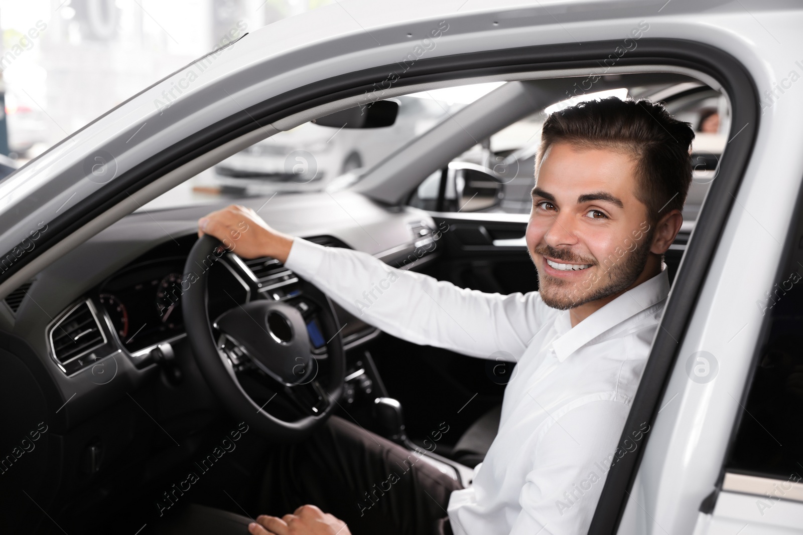 Photo of Young man testing new car in salon