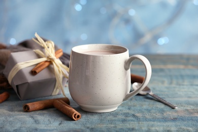 Cup with delicious hot cocoa drink and gift box on table