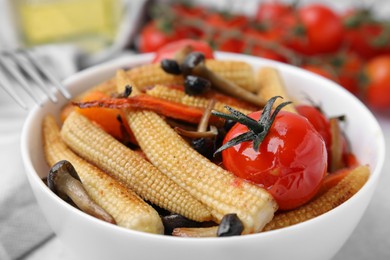 Photo of Tasty roasted baby corn with tomatoes and mushrooms on table, closeup