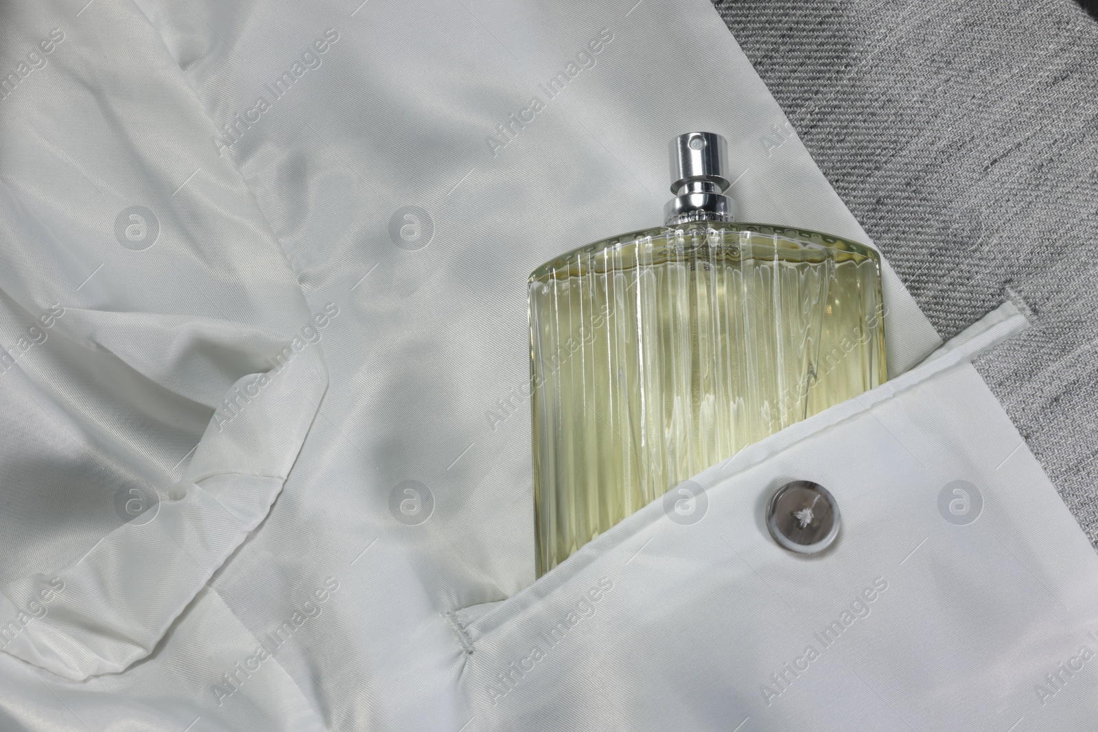 Photo of Luxury men's perfume in inner pocket of grey jacket, top view. Space for text