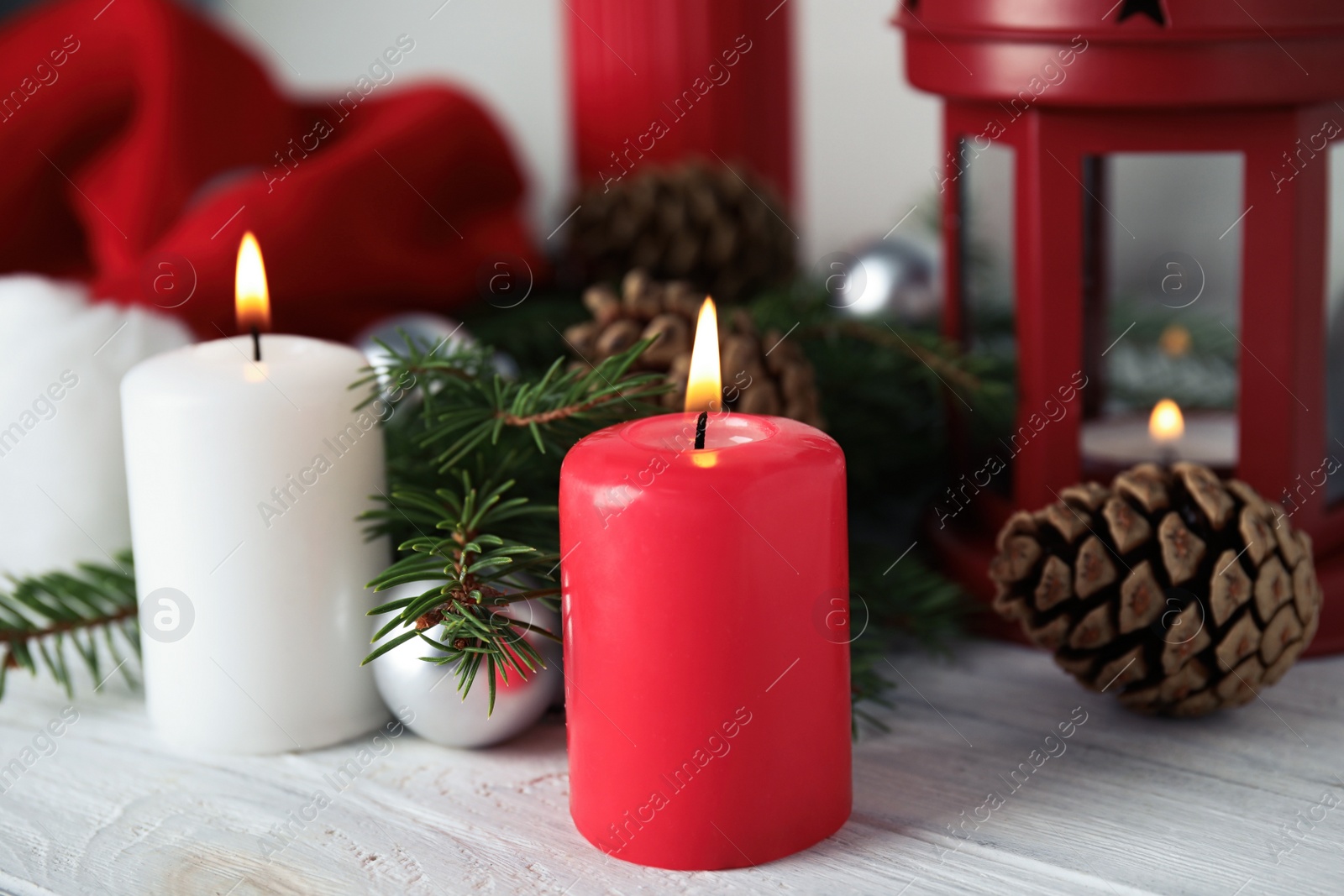 Photo of Burning candles and festive decor on white wooden table. Christmas eve