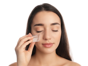 Photo of Young woman with ice cube on white background. Skin care