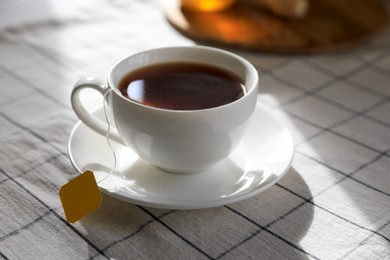 Photo of Bag of black tea in cup on table