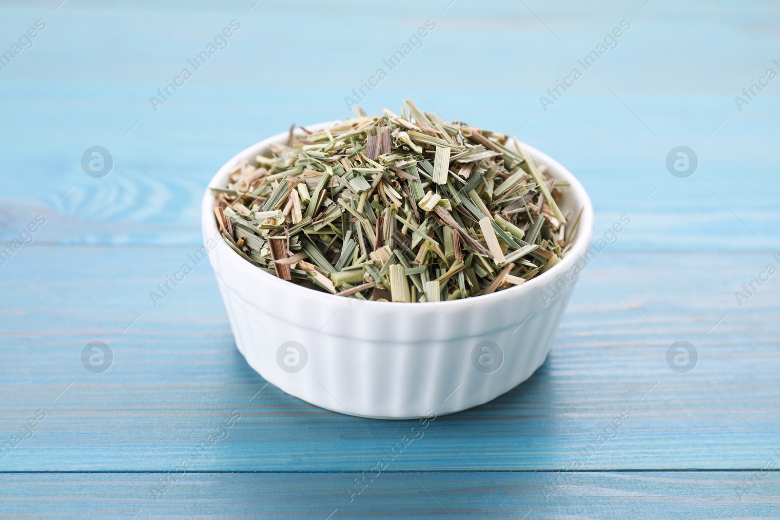 Photo of Bowl with aromatic dried lemongrass on light blue wooden table