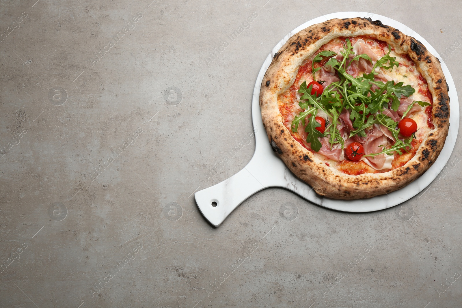 Photo of Tasty pizza with meat and arugula on grey table, top view. Space for text