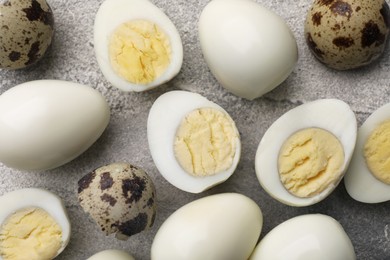 Peeled and unpeeled hard boiled quail eggs on grey table, flat lay