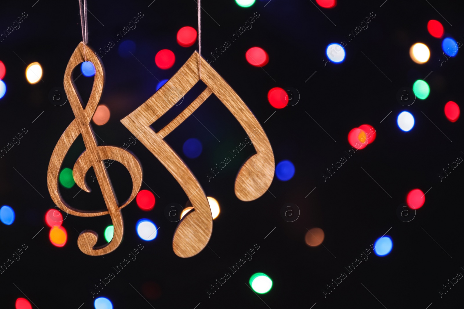 Photo of Wooden treble clef and note against defocused lights. Christmas music concept