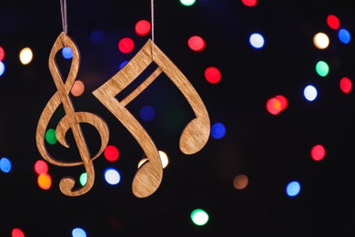 Wooden treble clef and note against defocused lights. Christmas music concept