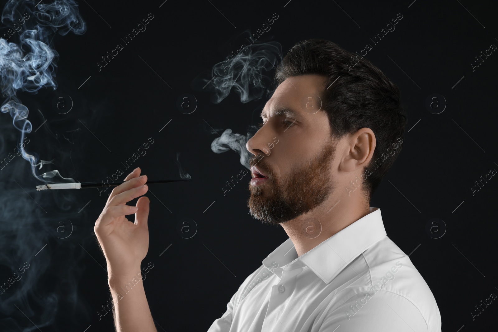 Photo of Man using long cigarette holder for smoking on black background