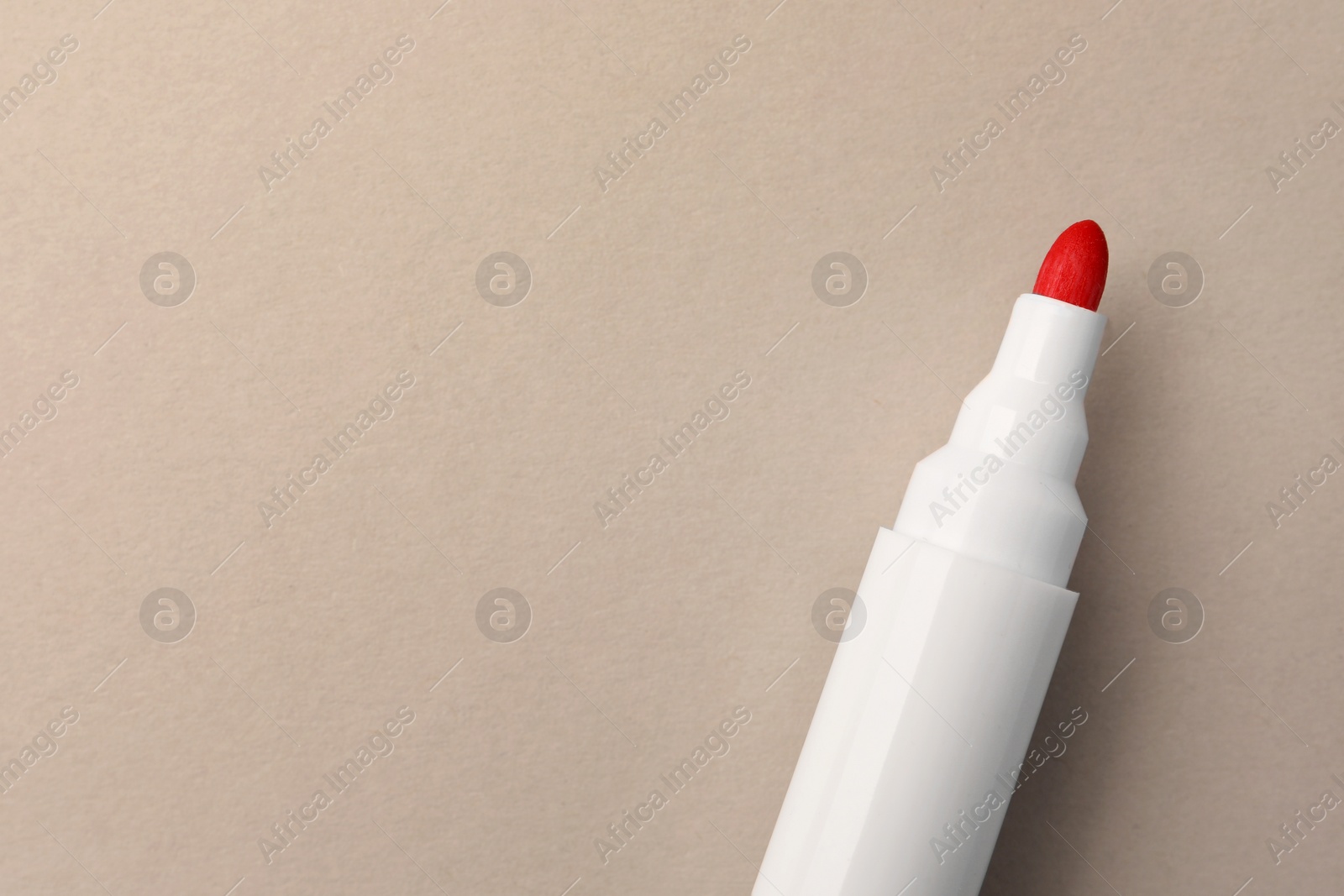 Photo of Bright red marker on beige background, top view. Space for text