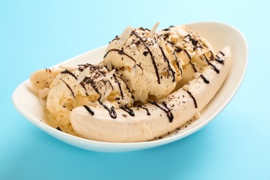 Photo of Delicious banana split ice cream with toppings on light blue background