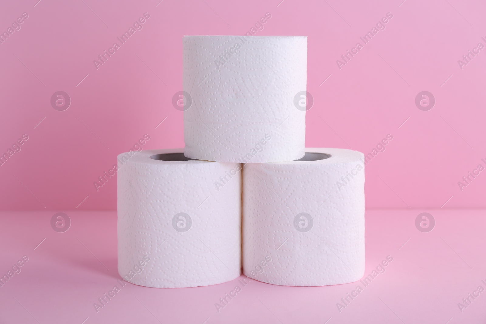 Photo of Soft toilet paper rolls on pink background, closeup