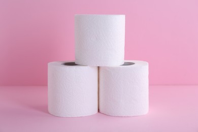 Photo of Soft toilet paper rolls on pink background, closeup