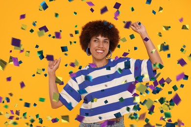 Image of Happy woman under falling confetti on orange background