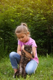 Photo of Cute little girl with cat in green park