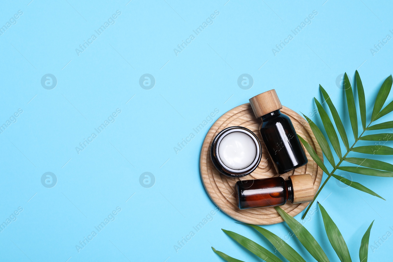 Photo of Flat lay composition with spa products and green leaves on light blue background, space for text