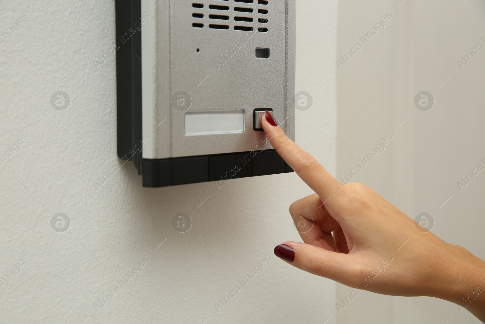 Photo of African-American woman pushing intercom button in entryway, closeup