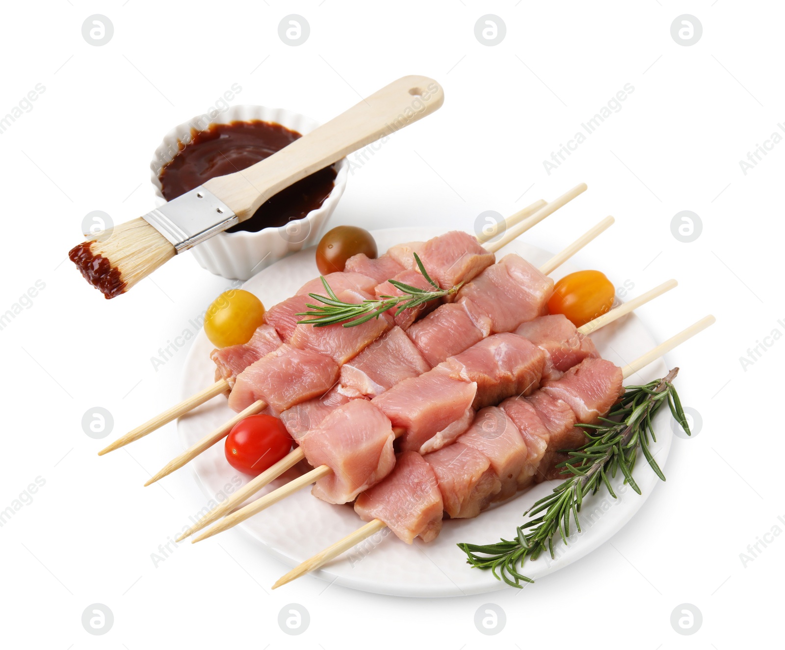 Photo of Skewers with pieces of raw meat, rosemary, tomatoes and marinade isolated on white