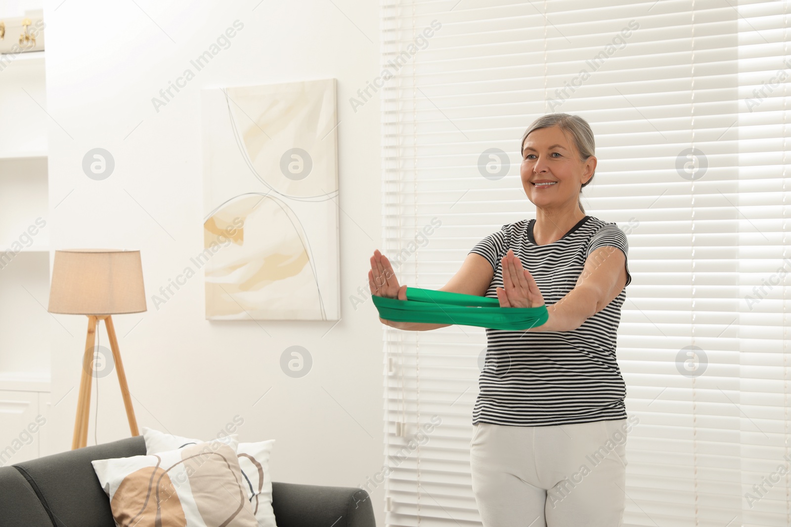 Photo of Senior woman doing exercise with fitness elastic band at home. Space for text