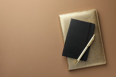 Photo of Different notebooks and pen on light brown background, top view. Space for text
