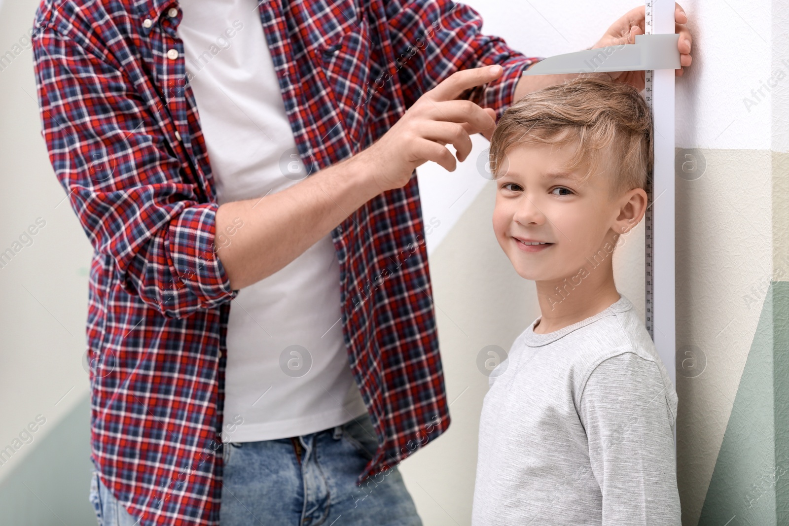 Photo of Young man measuring his son's height at home