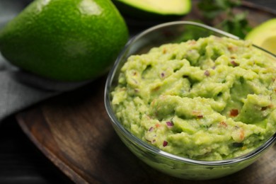 Photo of Glass bowl with delicious guacamole and fresh avocado on table, closeup. Space for text