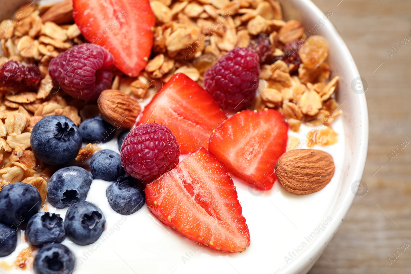 Photo of Tasty homemade granola served on wooden table, closeup. Healthy breakfast