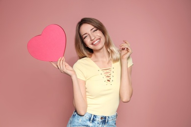 Photo of Portrait of beautiful smiling girl with heart shaped gift box on pink background. International Women's Day