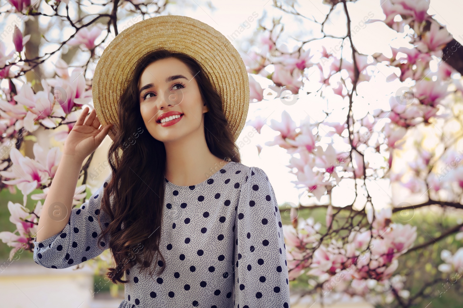 Photo of Beautiful woman near blossoming magnolia tree on spring day