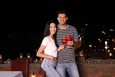 Photo of Romantic couple with glasses of cocktails on cafe terrace at night
