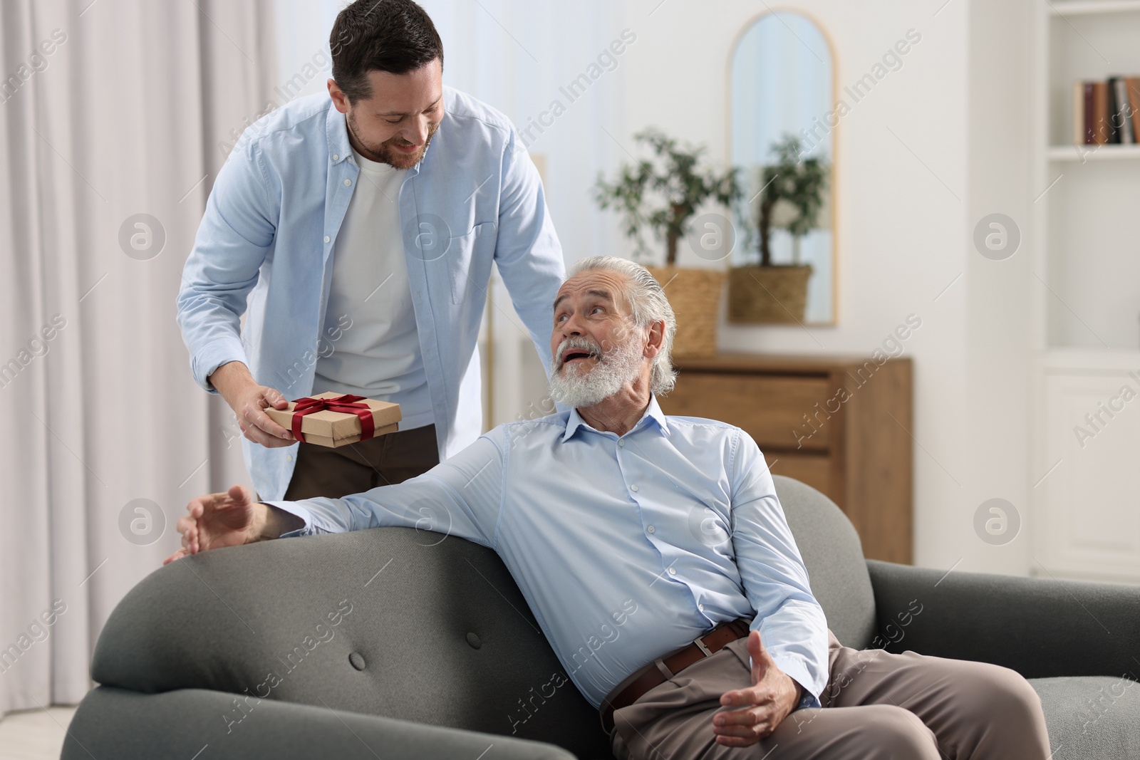 Photo of Son giving gift box to his dad at home