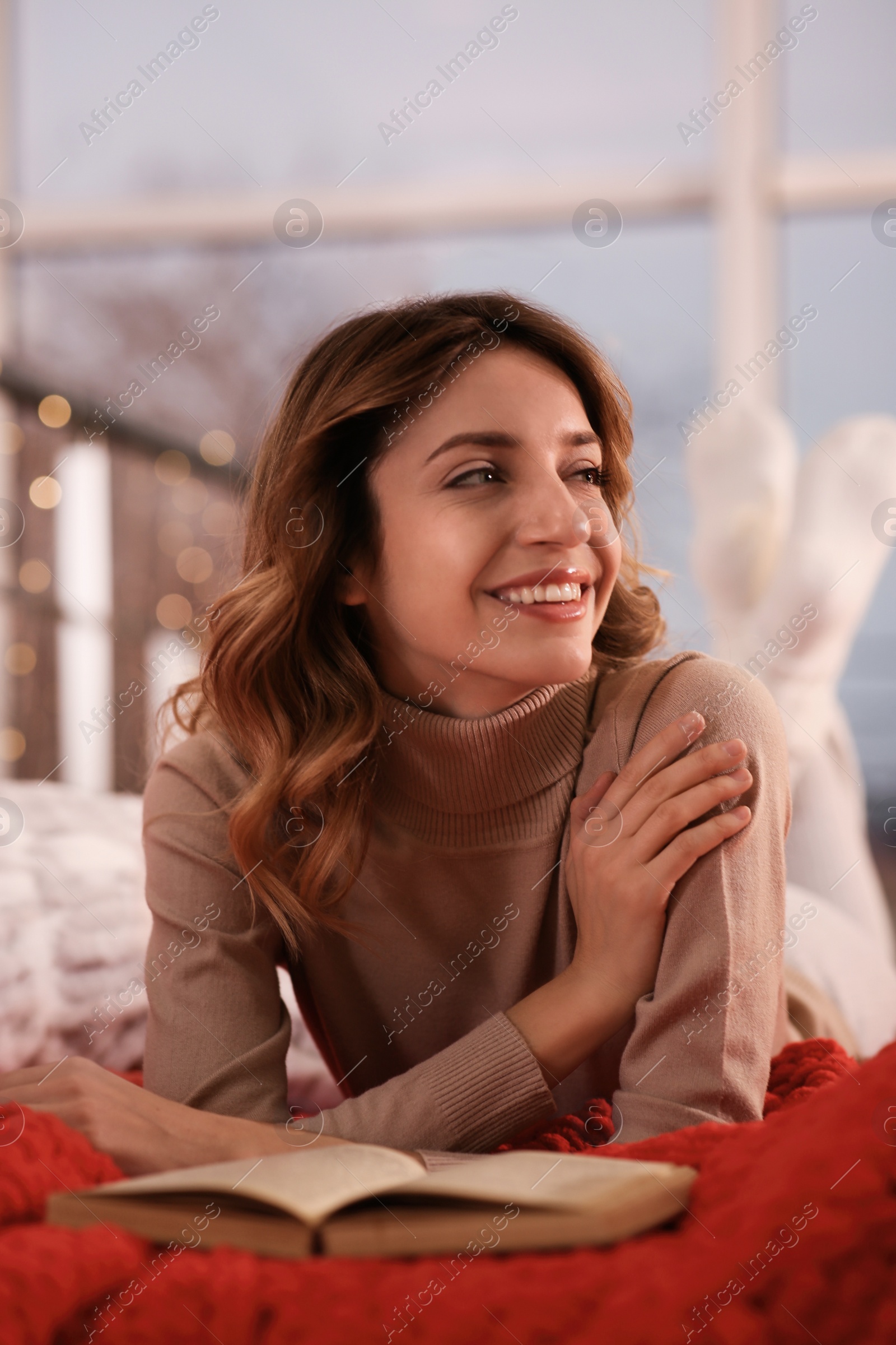 Photo of Beautiful young woman with book relaxing on bed at home. Cozy atmosphere