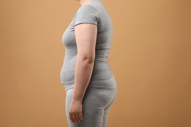 Overweight woman in grey clothes on beige background, closeup