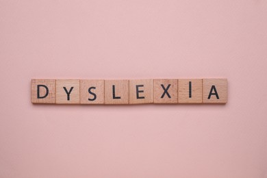 Photo of Wooden cubes with word Dyslexia on beige background, flat lay