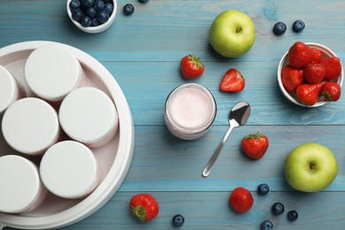 Photo of Modern yogurt maker with full jars and different fruits on light blue wooden table, flat lay