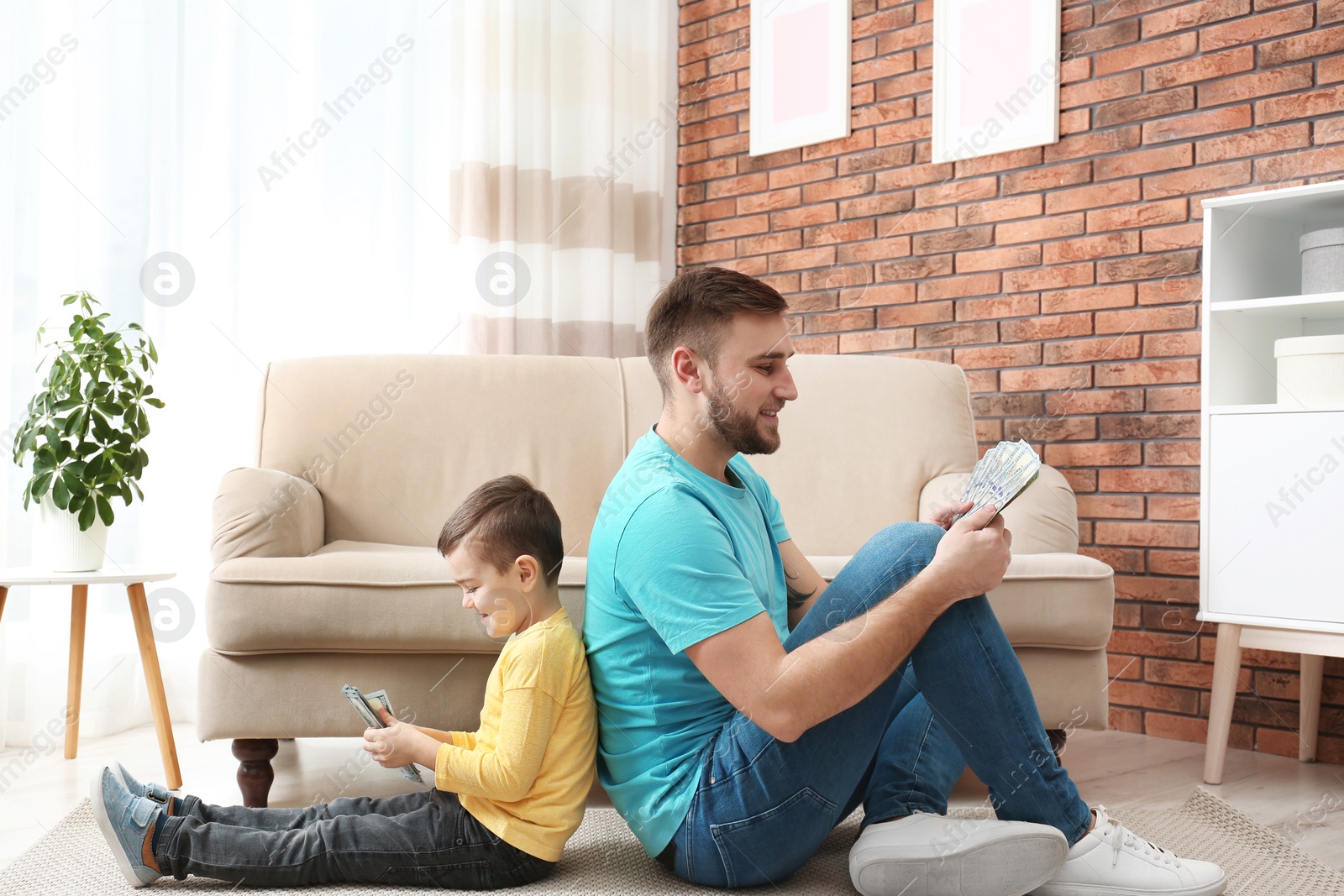 Photo of Happy father and son with money at home