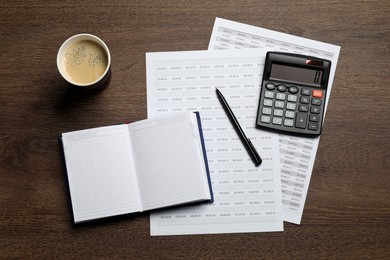 Calculator, coffee, notebook and documents with data on wooden table, flat lay