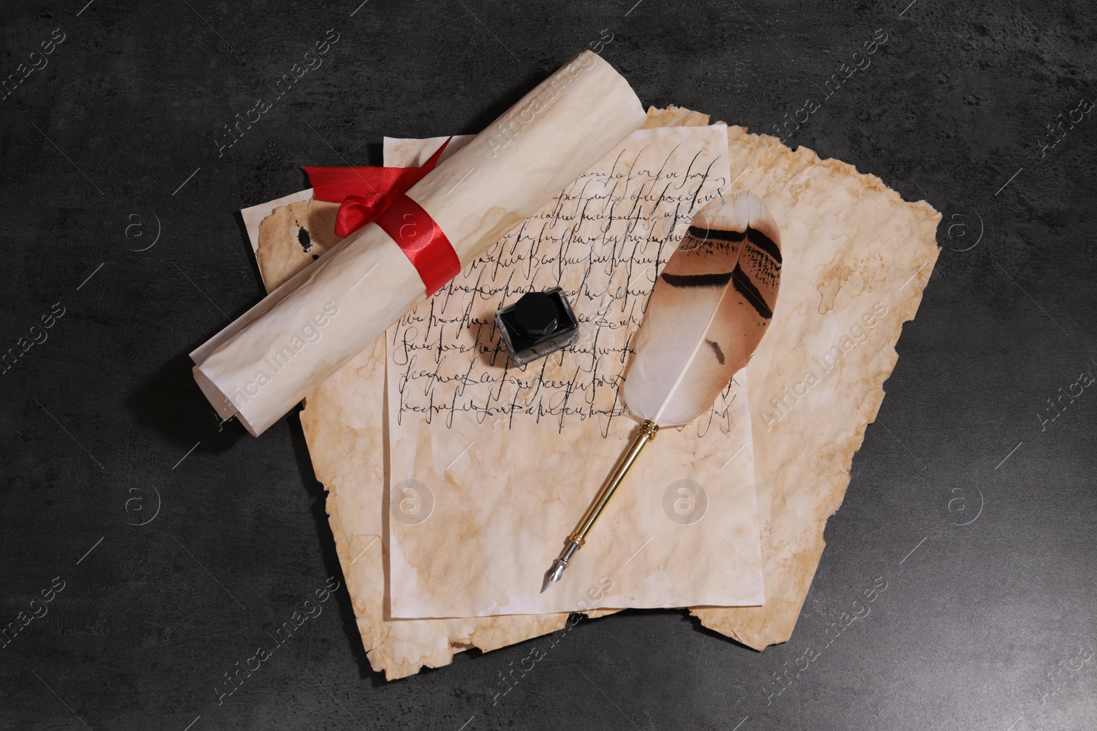 Photo of Feather pen, inkwell and vintage parchment on grey textured table, flat lay