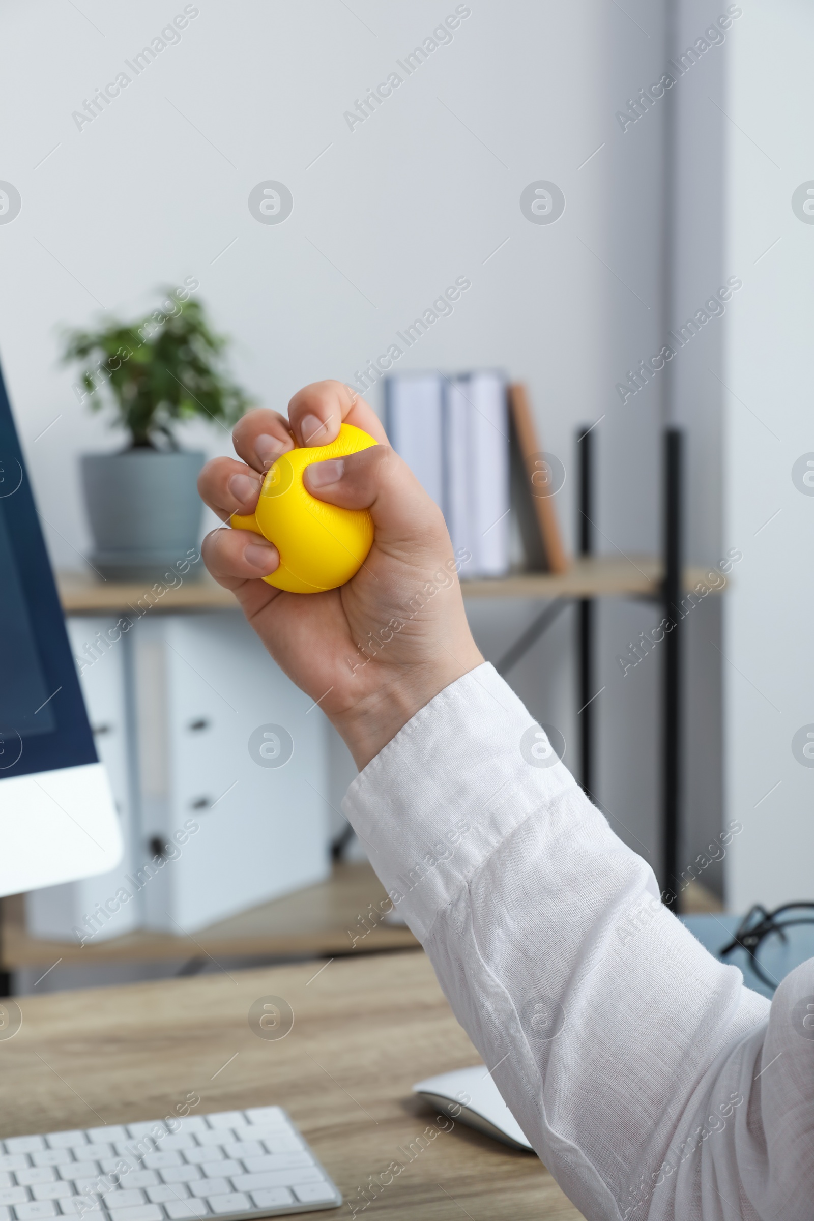 Photo of Man squeezing yellow stress ball in office, closeup