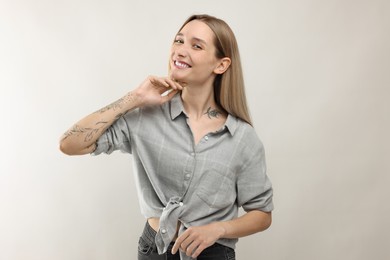 Portrait of beautiful tattooed woman on light background