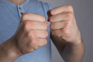 Photo of Man showing fists with space for tattoo on grey background, selective focus