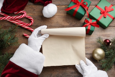 Santa Claus with blank paper and Christmas decor at wooden table, top view