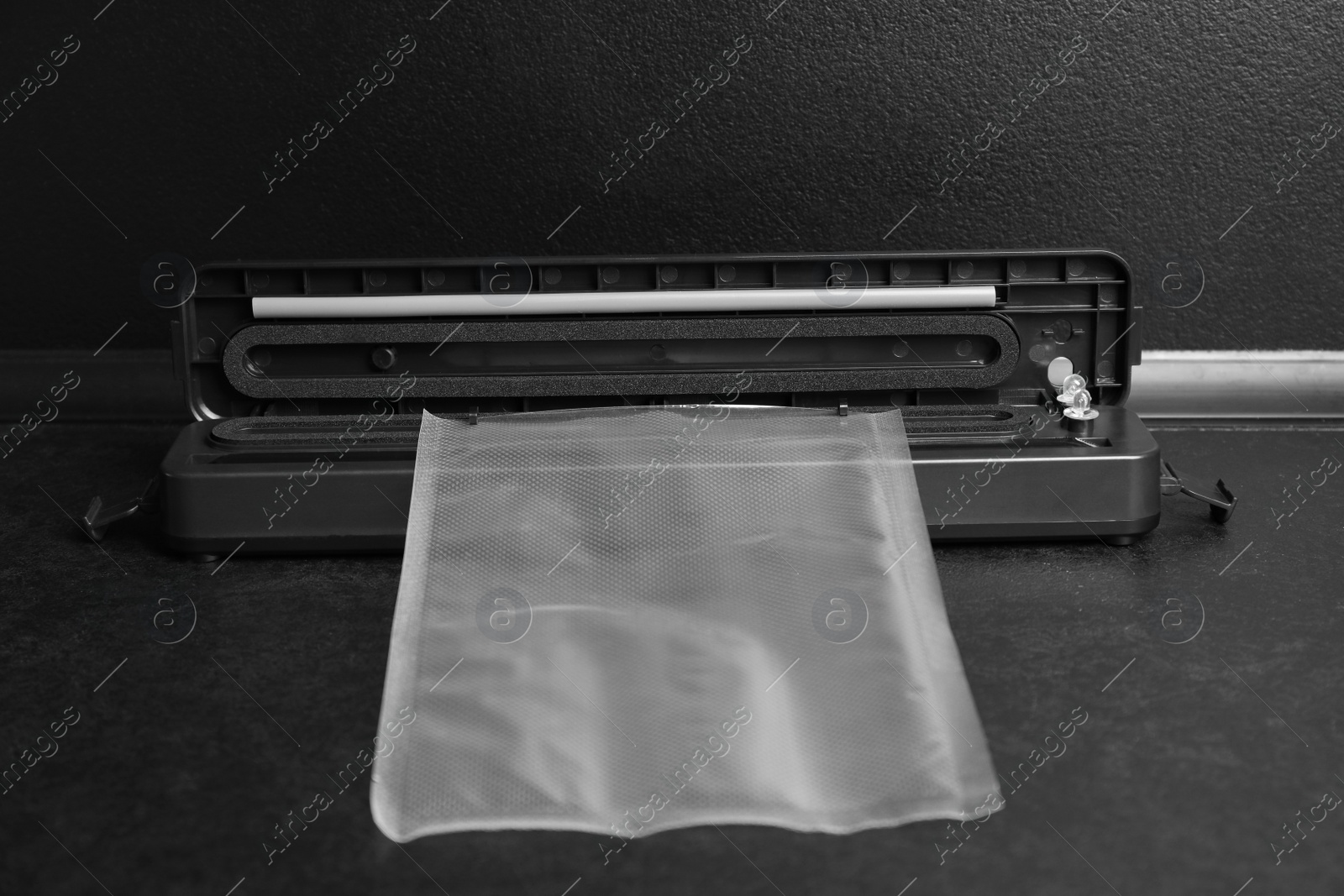 Photo of Sealer for vacuum packing with plastic bag on black table