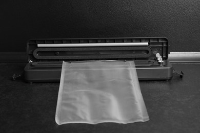Photo of Sealer for vacuum packing with plastic bag on black table