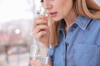 Photo of Young woman taking pill indoors