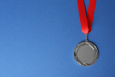 Silver medal on blue background, top view. Space for design