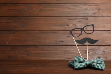 Photo of Paper moustache, glasses and bow tie on wooden background with space for text. Father's day celebration
